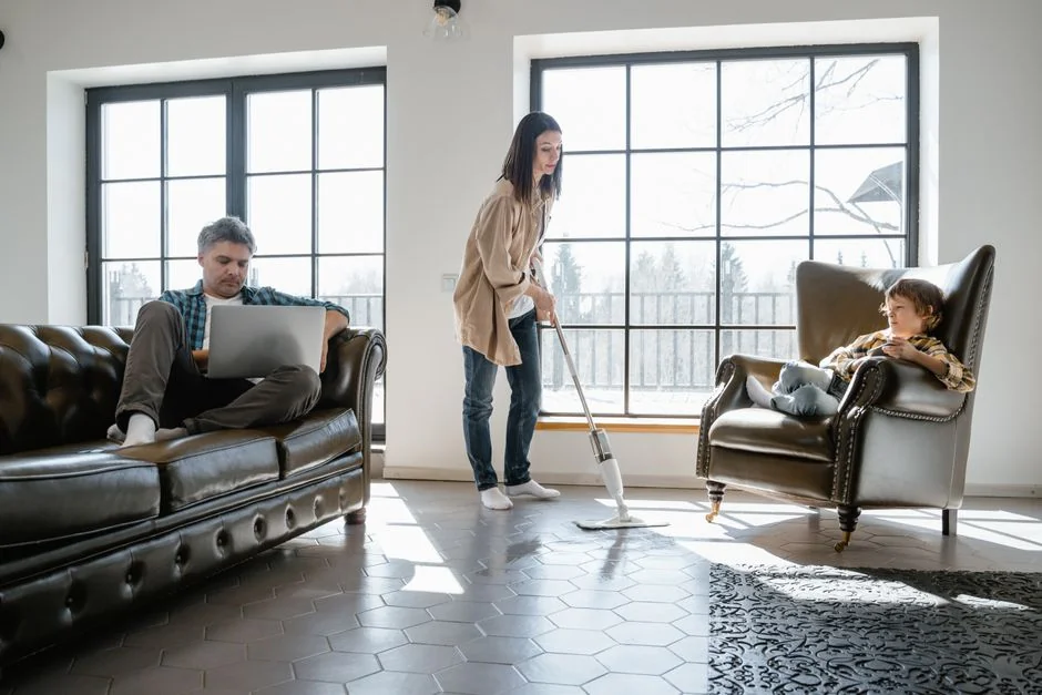 Une femme adulte en combinaison rouge utilise un aspirateur dans un environnement intérieur moderne, en se concentrant sur les tâches de nettoyage.
